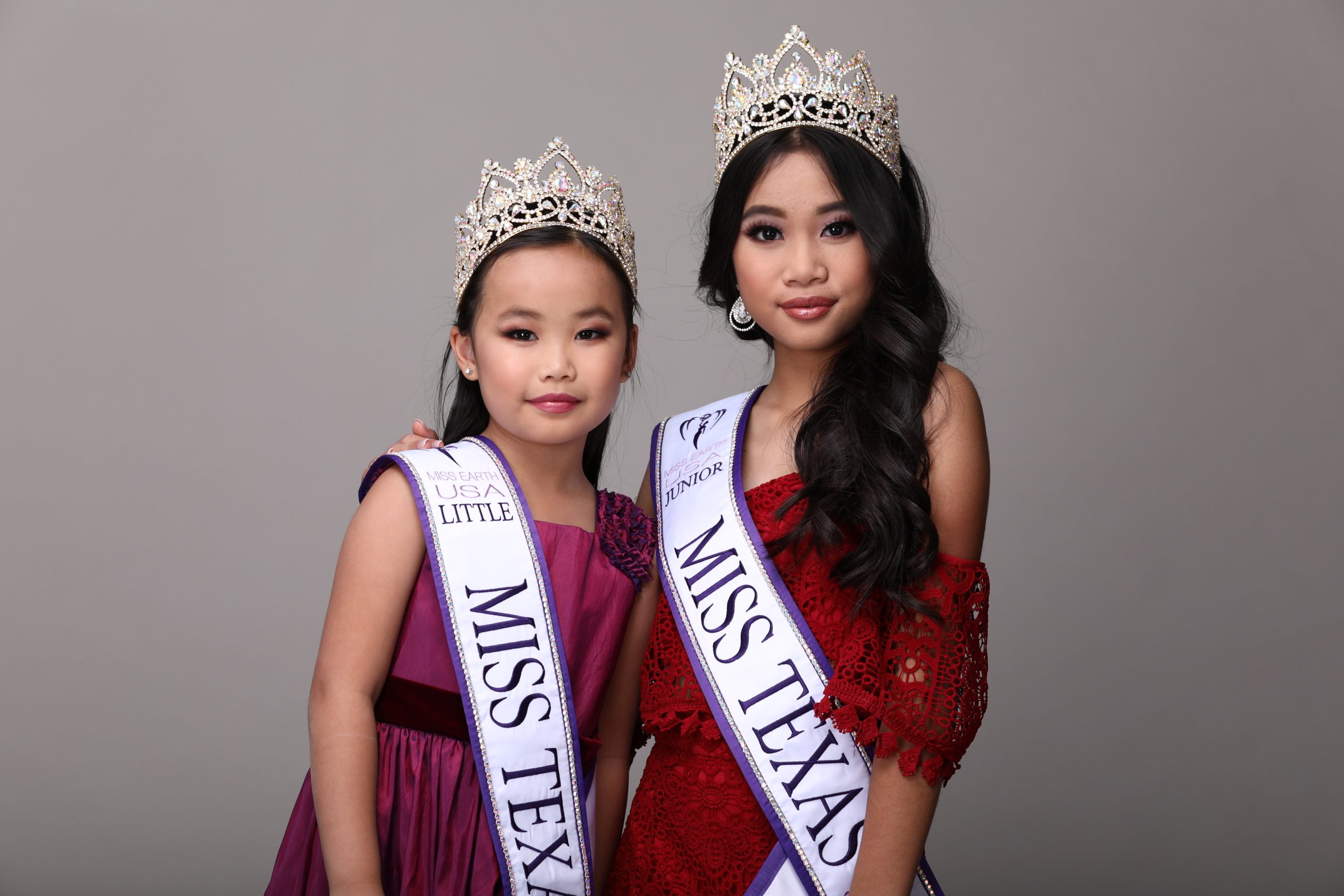 Angelvina Davina; Two girls wearing crowns and sashes, one labeled "Miss Texas USA Little," the other "Miss Texas," pose for a photo against a grey background.